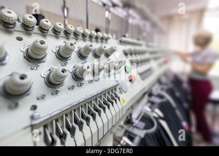 Stitching logos on restaurant uniforms with embroidery machine. Professional branding of chef workwear and kitchen staff apparel using multi head indu Stock Photo