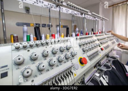 Colorful threads on industrial multi head embroidery machine. Automated equipment for branding restaurant uniforms and chef workwear in textile manufa Stock Photo