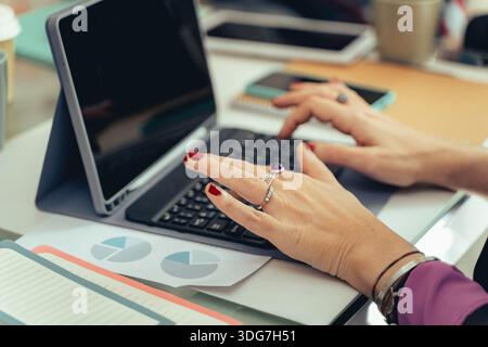 Close up of professional hands using a tablet keyboard while analyzing financial charts and business documents on an office desk. Concept of planning, Stock Photo