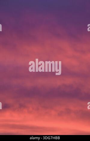 A powerful and dramatic sunset sky showing a deep transition from royal purple to intense, glowing red and orange hues. Stock Photo