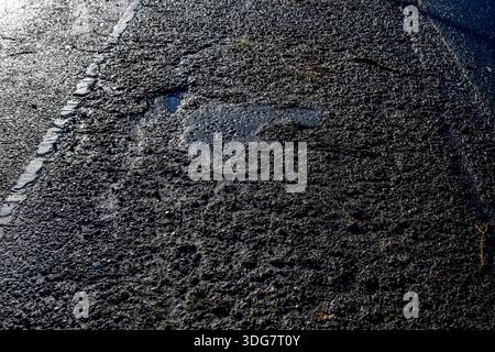 ROTTERDAM - Due to the severe frost and cold and the road salt, the asphalt has been damaged and broken. Road surface is damaged by frost because water seeps into small cracks in the asphalt, freezes, expands and thus damages the road surface, leading to loose stones, larger cracks and holes, especially after periods of frost with heavy rainfall and thaw. ROBIN UTRECHT /ANP netherlands out - belgium out Stock Photo