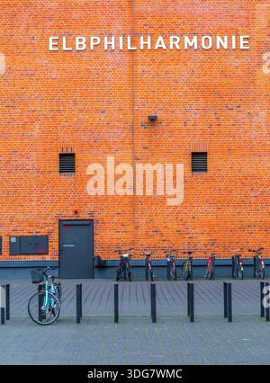 Hamburg Germany - February 21 2020. Minimalist view of the 'ELBPHILHARMONIE' text on the textured red brick wall. Black security door and bike racks a Stock Photo