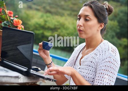 Remote working woman using laptop drinking coffee Stock Photo