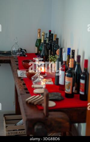 Industrial workbench used as a table at a birthday party, with wine bottles arranged on it and a burning candle creating a warm, intimate atmosphere. Stock Photo