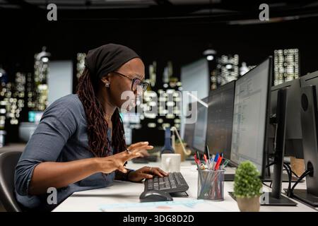 Technician typing on PC keyboard in startup office, optimizing code for performance and scalability, doing quality assurance. IT worker looking at programming language on computer Stock Photo