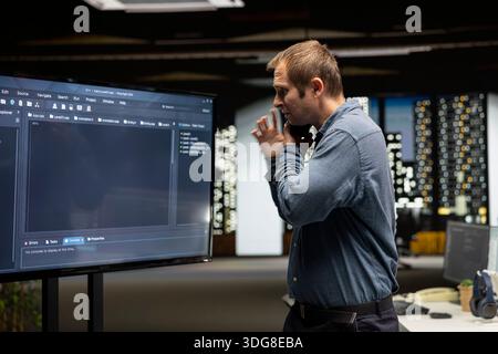Startup manager looks at code written by workers, thinking how to leverage it to gain competitive edge. Supervisor looks at coding script on large screen, working on technological advancements Stock Photo