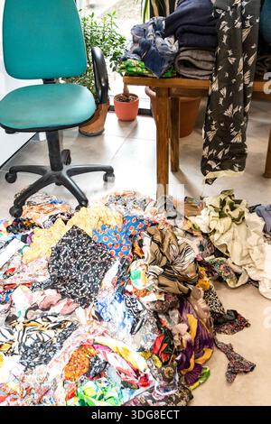 Pile of colorful fabric scraps on studio floor, showing creative process, textile reuse, and sustainable fashion workspace. Stock Photo