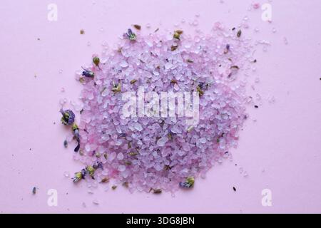 Purple bath and spa salts with dried lavender on a pink background. Natural body care cosmetics. Stock Photo
