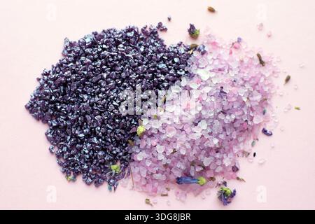 Purple bath and spa salts with dried lavender on a pink background. Natural body care cosmetics. Stock Photo