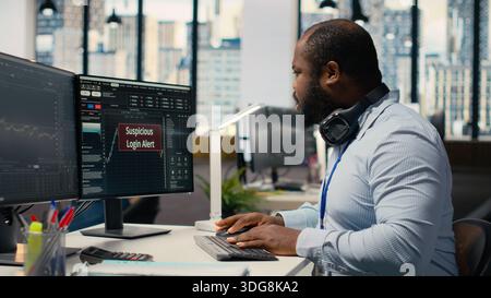 Forex investment consultant investigating suspicious access on trading account. African american man in office worried about security popup on PC about attempted breach of client account Stock Photo