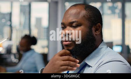 Close up of trader analyzing stock exchange analytics, doing thinking, evaluating trading strategy in prop firm office. African american man brainstorming, assesses risk in financial markets Stock Photo