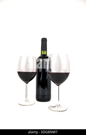 Studio photo of two glasses filled with red wine in front of an unbranded bottle, isolated on white with copy space for celebration, dining and tastin Stock Photo