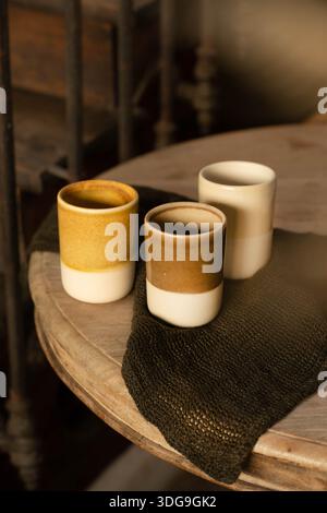 A set of three artisanal ceramic cups without handles, featuring a beautiful crackle glaze finish in earthy yellow, brown, and cream tones. Stock Photo