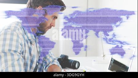 Leaning bearded man in checked shirt using laptop at desk with camera, purple overlay, copy space Stock Photo