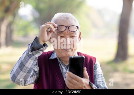 Poor Eyesight. Senior  Man Using Smartphone Wearing Eyeglasses Stock Photo