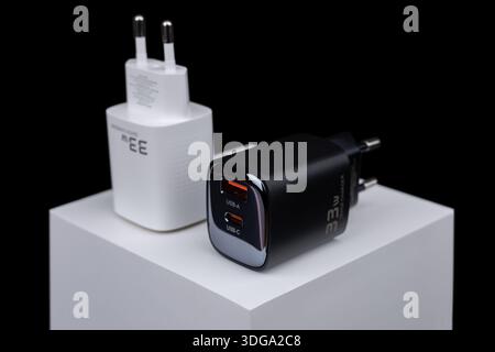 white and black smartphone chargers on dark background. Charger and USB cable type C on dark background. Stock Photo