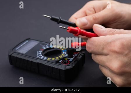 Cropped image of male repairman checking fridge with digital multimeter at home. Stock Photo