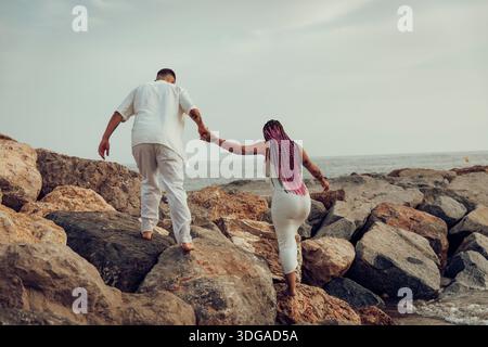 Maternity photo of a young couple walking barefoot on the beach Stock Photo