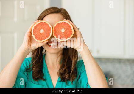 Beautiful Woman Holding Ruby Red Grapefruit Cut in Half Stock Photo