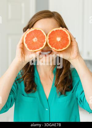 Beautiful Woman Holding Ruby Red Grapefruit Cut in Half Stock Photo