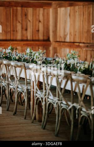 long formal dinner table in a barn with flower arrangements Stock Photo