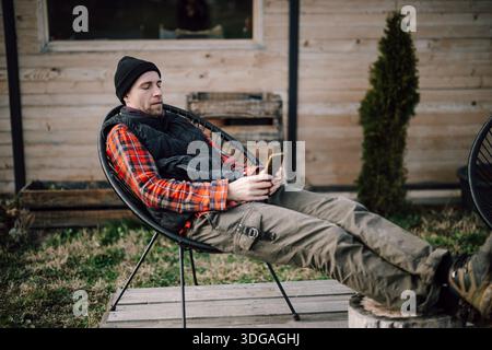 Man sitting outside on a chair and using a smartphone Stock Photo