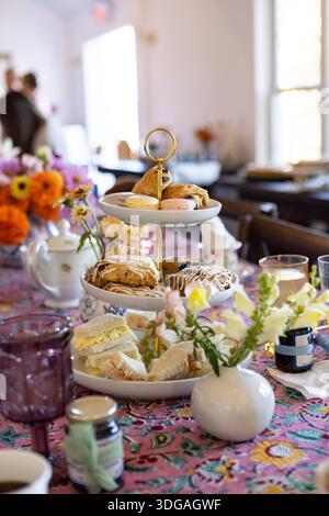 Tiered stand of pastries on a table decorated with flowers Stock Photo