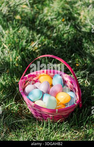 Pink Easter basket filled with eggs sitting in grass. Stock Photo