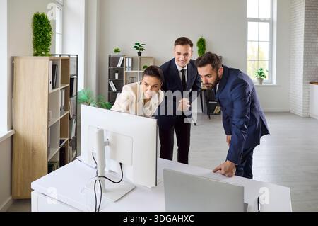 Corporate team discussing strategy at computer in bright office, analyzing data Stock Photo
