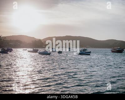 Harbor at sunset with small boats anchored on calm water and warm sun flare Stock Photo