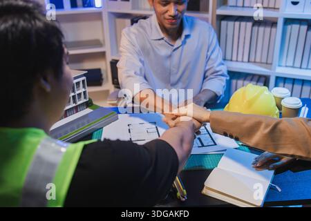 A group of engineers and architects collaborate on a construction project, discussing ideas and sharing technical plans to design innovative modern bu Stock Photo