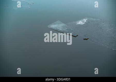 Broken Ice Sheets Floating on Calm Water Surface in Winter Stock Photo