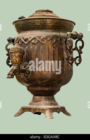An antique brass water boiler, known as a samovar, with a tarnished finish and ornate details on isolated green background with clipping path. Stock Photo