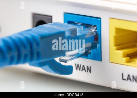 Blue network twisted pair cable connected to the WAN port on the modern wi-fi home router. Close up macro image. Stock Photo