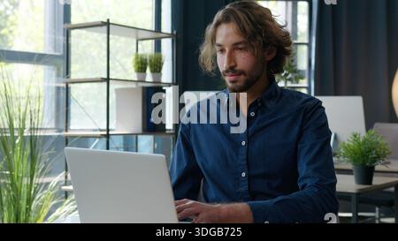 Hispanic business man working typing laptop reading paper businessman work with computer analyzing online data at table in office manager guy male Stock Photo
