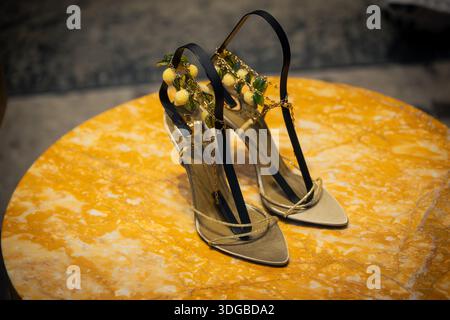Milan, Italy - 2026, 13 Jan: Elegant Saint Laurent FW25 heels with lemon embellishments displayed on a yellow marble table, highlighting luxury and cr Stock Photo