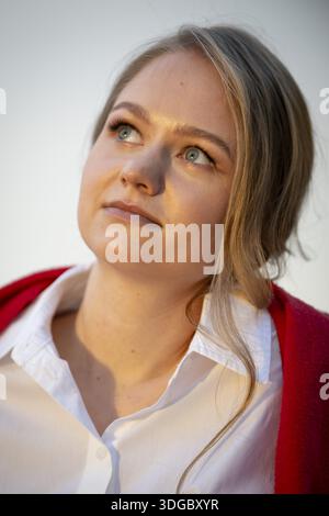 Portrait of a thought-looking young woman, pianist, wearing white blouse and red cardigan, in the evening light, Stuttgart, Baden-Wuerttemberg, German Stock Photo