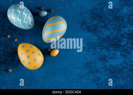 Decorated Easter eggs in blue and orange hues arranged on a textured blue surface. 3d rendering Stock Photo