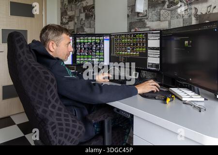 Man editing video on multi-monitor workstation setup. Focused man working at home office with triple monitors, editing videos using professional Stock Photo