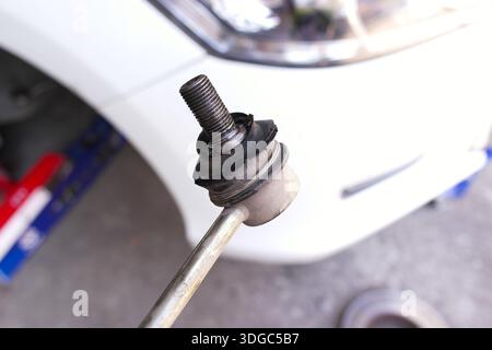 Damaged Car Suspension Part, Close-up of a worn stabilizer link with a torn rubber boot, showing signs of damage and needing repair for vehicle safety Stock Photo