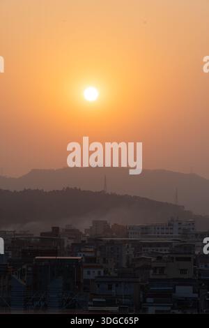 Sunset over urban cityscape with distant mountains - West Lake in Huizhou, Guangdong Province, China, is a tourist attraction featuring ancient architecture Stock Photo