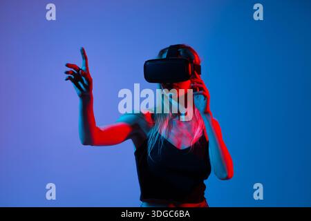 Side view of woman using VR headset and gesturing with finger, immersive virtual experience and future technology Stock Photo