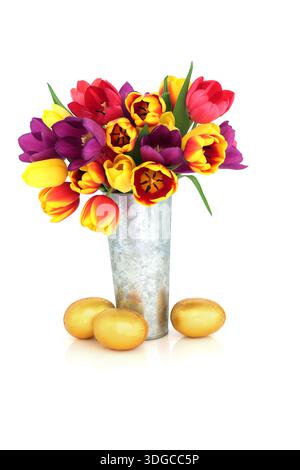 Tulip spring flowers and gold easter egg design on white background, metal vase still life arrangement with luxury eggs for the festive season. Stock Photo