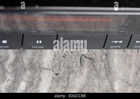 Macro shot of a CD player control bar revealing play, pause and stop icons on a sleek dark panel. The textured background adds a modern, tech-forward Stock Photo