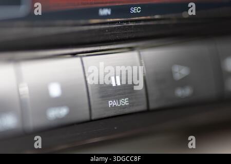 A close-up view of a car stereo featuring a prominent pause button, showcasing sleek metallic controls and a blurred dashboard. Ideal for themes of mu Stock Photo