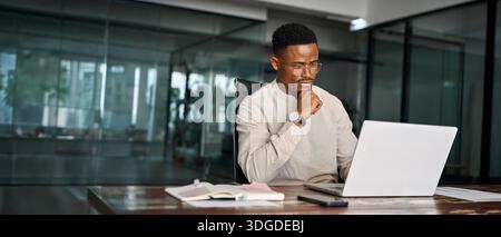 Busy African business man thinking on online investment working on laptop. Stock Photo