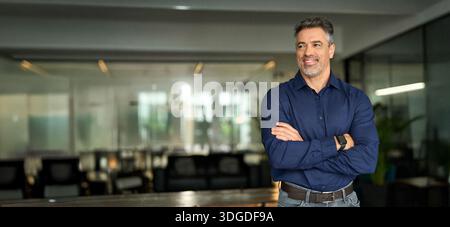 Smiling middle aged business man leader standing looking away in office. Stock Photo