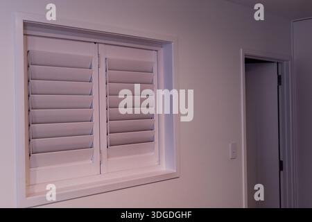 Closed White Shuttered Window Beside Interior Door Stock Photo