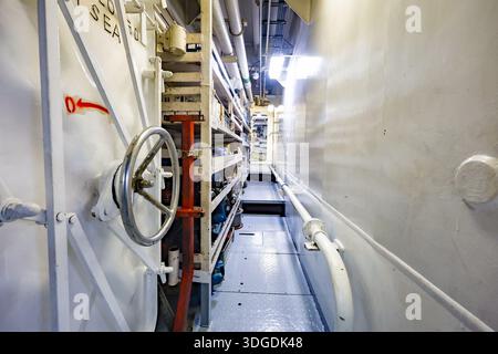Industrial storage corridor with shelves, containers and spare parts inside a technical machinery room, organized workspace with equipment Stock Photo