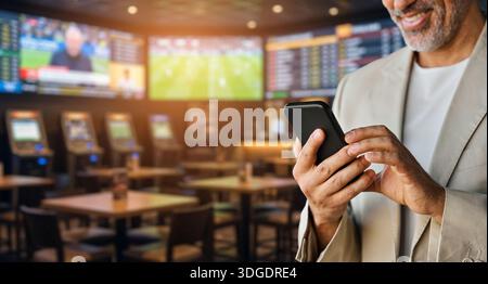 Happy man standing using gambling app on smartphone. Banner Stock Photo